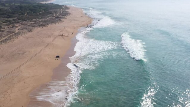 Aerial drone view of surfer sitting on his board watching the waves coming by.