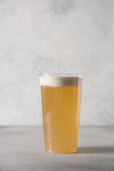 Cheese oolong tea with layer of cream cheese in plastic cup. Vertical format. Close up. Popular Chinese asian beverage.