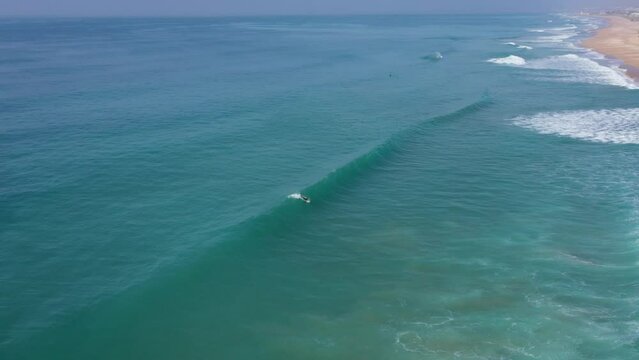Aerial drone view of surfer sitting on his board watching the waves coming by.