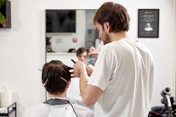 young caucasian man getting haircut by professional male hairstylist