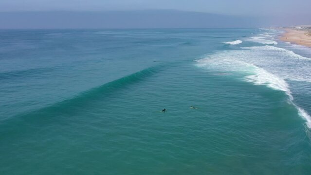 Pro surfer riding a long wave in El Palmar, Spain. Drone video of a surfer doing an aerial 360 trick on surfboard.