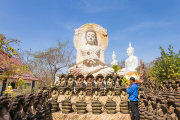 Kalasin, Thailand - February 1, 2023. Buddhist men worship a carved stone Buddha image  at Phu Dan Hai Temple, Kuchinarai District Kalasin Province, Thailand.