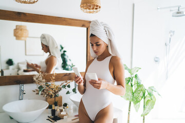 Focused woman studying cosmetic tubes to use after bath
