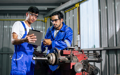 Portrait two handsome male mechanics wearing uniform, using machine for fix, repair car or automobile components, teamwork helping, working in car maintenance service center or shop. Industry Concept.