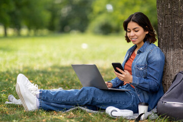 Modern Technologies. Smiling Young Arab Woman With Smartphone And Laptop Relaxing Outdoors