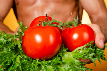 Young attractive Man with an athletic body on a diet. Orange background. Healthy food.