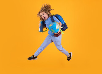 Fototapeta na wymiar Shool kid jump with school bag and globe. Funny excited school concept. Little student boy with backpack go to study, jumping. Schoolchild, pupil jump on yellow isolated background.