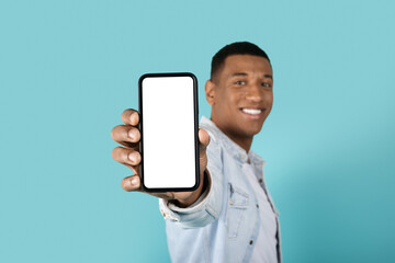 Glad confident millennial black male showing smartphone with empty screen