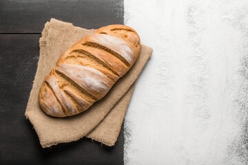 loaf of bread on wooden table, perfect bread to accompany your healthy meals on a brown wooden table with part covered in flour