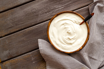 White sauce sour cream or yogurt in wooden bowl, top view