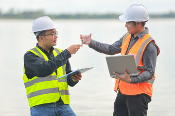 Environmental two engineers work at water source to check for contaminants in water sources and analyzing water test results for reuse.World environment day concept.