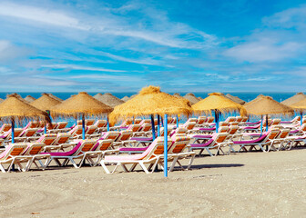 Strand mit rosa Liegen und Strohschirmen