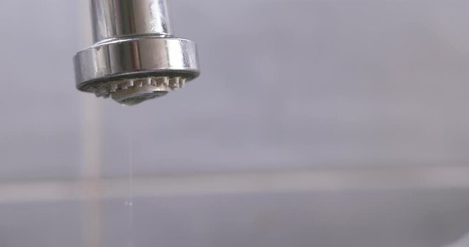 Drops fall from a leaking tap in the bathroom.