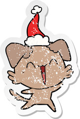 happy little dog distressed sticker cartoon of a wearing santa hat
