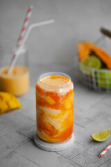 Tropical smoothie on a light background. Drink Lassi made of yogurt, papaya, mango, other tropical fruits, spices and ice. Close-up.