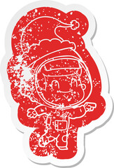 happy cartoon distressed sticker of a astronaut man wearing santa hat