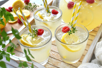 A tray of cool summer drinks, herbal lemonade with raspberries and thyme herb, cocktail.