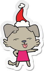 sticker cartoon of a dog sticking out tongue wearing santa hat