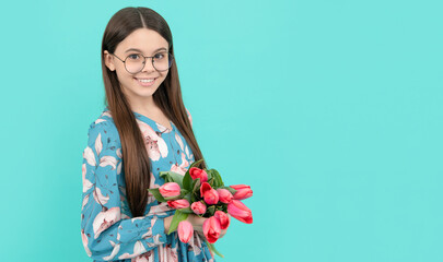 kid hold flowers for 8 of march. teen girl with spring bouquet on blue background.