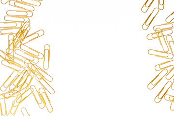 Many golden paper clips laid out together against a white background