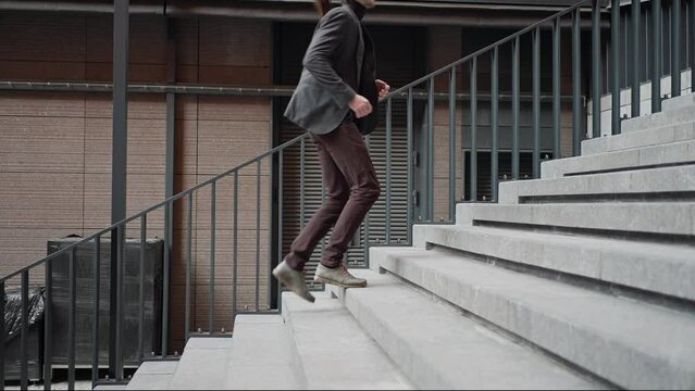 Side view of caucasian young businessman in stylish suit walking up on stairs. Busy male employer in hurry. Carier grow, moving up and forward