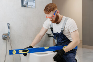 Professional plumber working with toilet bowl in bathroom. Concept repair service plumbing
