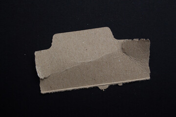 Ripped paper piece on an isolated black background. Top view, copy space.