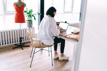 Female dressmaker with laptop in studio