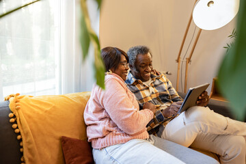 elderly couple video call with a tablet on the sofa at home