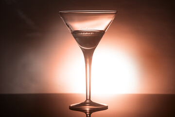 glass goblet with a drink in the back colored light, the concept of minimalism, noir style, subject.