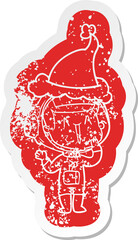laughing cartoon distressed sticker of a astronaut wearing santa hat