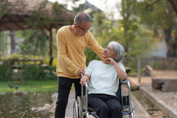 Fototapeta na wymiar Elderly couple. Asian couple giving love to each other smiling happily. Asian old husband caring and giving love to his wife in wheelchair.