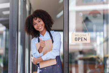 Female store owner or staff, food, cafe or bar, showing the OPEN sign with a welcome smile, welcome.