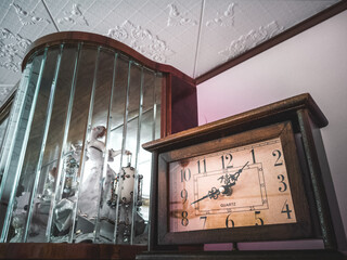 Old Fashioned Quartz Clock With A Wooden Cabinet In The Background, Ceramic Dancing Woman In The Cabinet