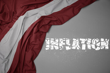 waving colorful national flag of latvia on a gray background with broken text inflation. 3d illustration