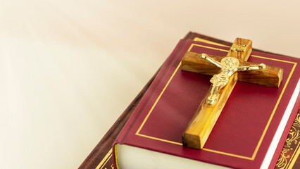 Religion composition with wooden crucifix with closed red Christian bibles on a light gradient background with divine light. Bible and Scripture Study. Religious church holidays. Copy space