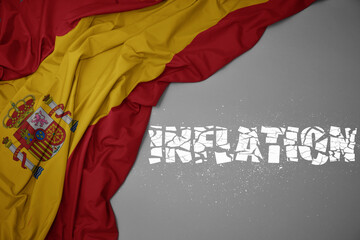 waving colorful national flag of spain on a gray background with broken text inflation. 3d illustration