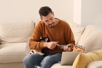 Man learning to play guitar with online music course at home. Time for hobby