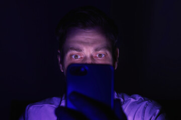 Man using smartphone at night, closeup. Internet addiction