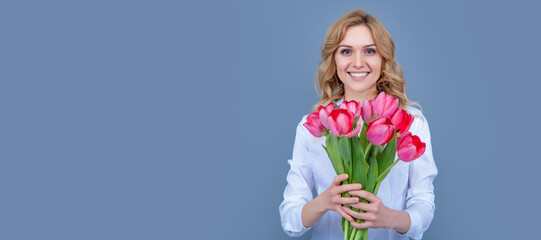 Girl with spring tulips flowers. glad blond woman with spring tulip flowers on grey background. Woman isolated face portrait, banner with mock up copy space.
