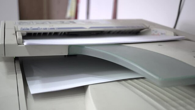 Closeup of aser jet printer printing A4 paper pages in a storehouse or a business office