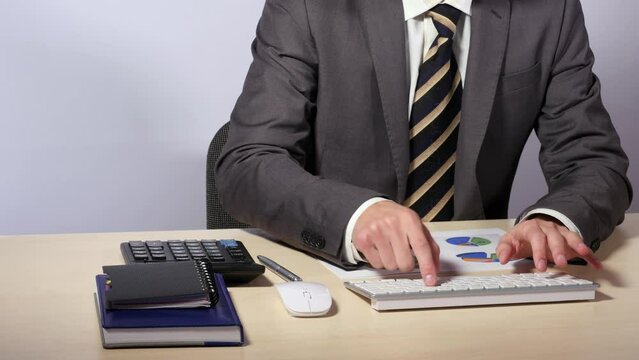 Businessman types on white keyboard, takes out from inner pocket of his grey suit plastic card and enters information on computer, press enter, bank operations in business. Close up, 4K Ultra HD.