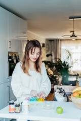 Woman sorting pills into pills organizer with her cat on the kitchen. Pill box with daily doses of medicines. Antioxidant diet vitamin supplements for health and beauty care, biohacking concept.