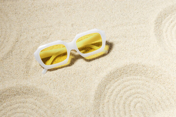 Fototapeta na wymiar Modern White sunglasses on beach sand background at sunlight with shadow. Summer fashion eyeglasses with yellow glass. Summer vacation, summer rest concept. Minimal style trend flat lay