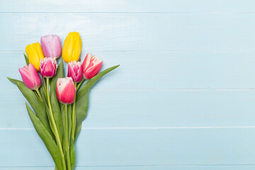 Bright tulips on wooden background, top view