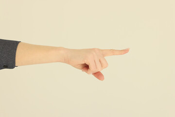 Hand of woman pointing index finger on beige background