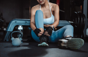 Naklejka premium Woman exercise workout in gym fitness breaking relax after training sport with kettlebell, dumbbells and water bottle healthy lifestyle bodybuilding.