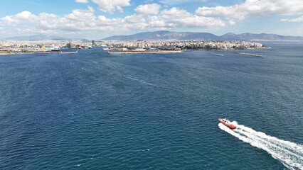 Aerial drone photo of red pilot boat cruising in high speed in Mediterranean deep blue sea reaching famous port of Piraeus, Attica, Greece