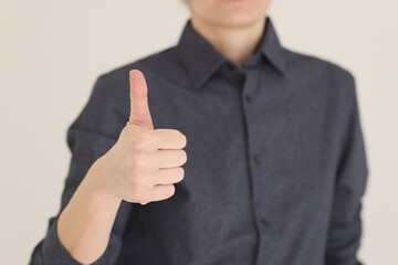 Woman shows thumb up gesture standing on beige background