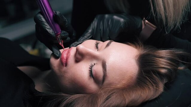 Permanent lip makeup. The cosmetologist makes the procedure of permanent makeup to the client in the salon. Close up.